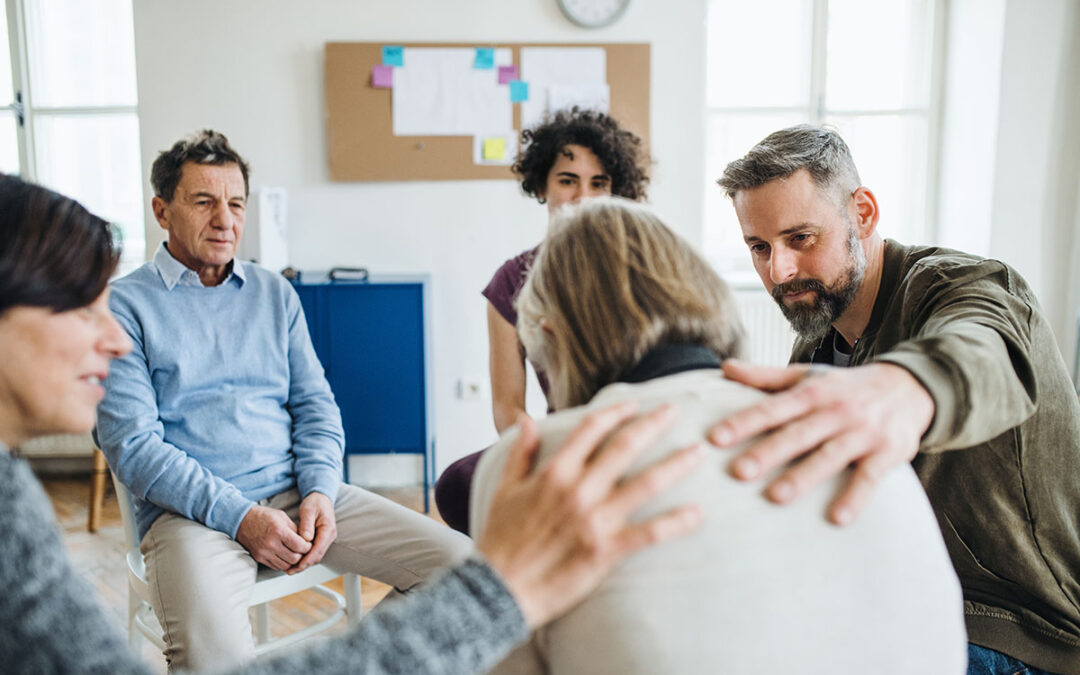 Men and women sitting in a circle during group therapy, supporting each other