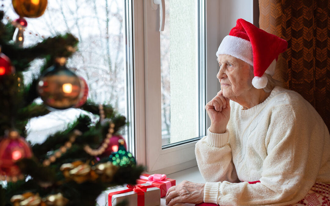 Sad elderly person on a window wearing Christmas hat